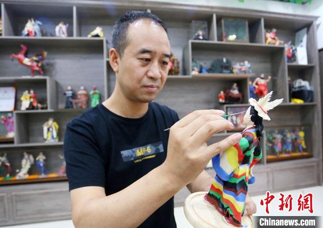 圖為安秋平正在創(chuàng)作代表隴南文縣民俗的《白馬人》作品。　高展 攝