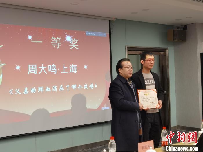 圖為作家、西北師范大學(xué)新聞與傳媒學(xué)院院長(zhǎng)徐兆壽頒發(fā)一等獎(jiǎng)證書，代領(lǐng)獎(jiǎng)?wù)呱吓_(tái)領(lǐng)獎(jiǎng)?！钅?攝