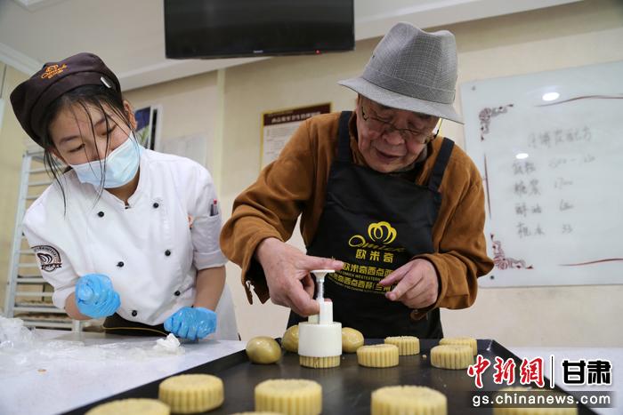 當日，受邀參加活動的臺胞臺屬代表、兩岸婚姻及子女、在甘臺商代表等歡聚一堂。圖為77歲的在甘臺胞潘天鑒制作月餅。九美旦增 攝
