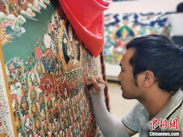 圖為更登才讓的徒弟繪畫唐卡?！?zhí)砀?攝