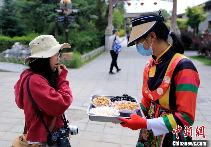 圖為身穿土族服飾的女性介紹當(dāng)?shù)靥厣〕??！⊙Φ?攝