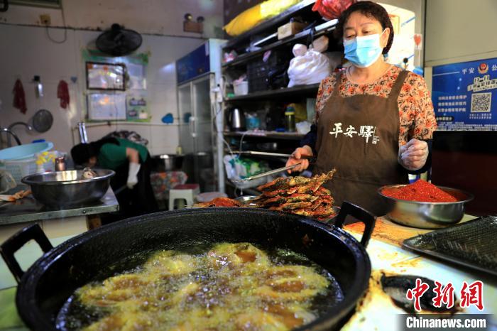 圖為平安驛·河湟民俗文化體驗地內(nèi)的商戶炸干板魚。　薛蒂 攝