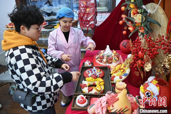 1月25日，隨著春節(jié)臨近，蘭州一花饃店“龍”元素花饃熱銷。圖為工作人員向顧客推薦“龍”元素花饃。九美旦增 攝</p><p>