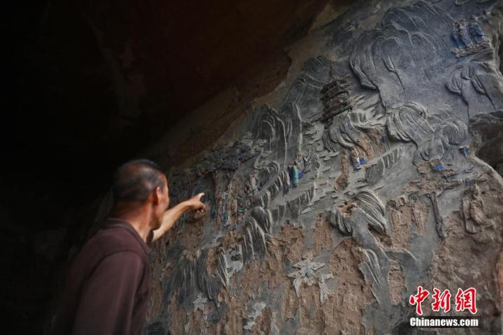 7月15日，甘肅省平?jīng)鍪袥艽h百里石窟長(zhǎng)廊羅漢洞石窟內(nèi)，該窟文保員郭建平介紹窟內(nèi)石刻彩繪壁畫(huà)。郭建平家中三代人曾自發(fā)保護(hù)羅漢洞石窟。羅漢洞石窟遺存40余個(gè)窟龕，以北魏至清代風(fēng)格為主。中新社記者 李亞龍 攝