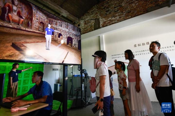 7月22日，游客體驗(yàn)“尋境敦煌——數(shù)字敦煌沉浸展”后，在虛擬演播廳拍攝一段真人與洞窟虛擬場(chǎng)景交互的視頻。新華社記者 郎兵兵 攝</p>
<p>