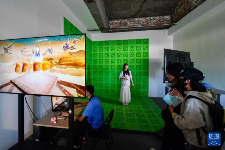 7月22日，游客體驗(yàn)“尋境敦煌——數(shù)字敦煌沉浸展”后，在虛擬演播廳拍攝一段真人與洞窟虛擬場(chǎng)景交互的視頻。新華社記者 郎兵兵 攝</p>
<p>